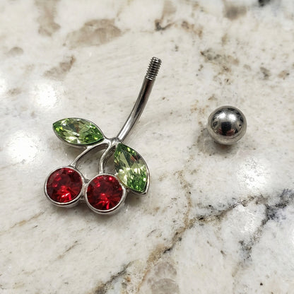 Cherry Red Green CZ Belly Ring 14G 316L Surgical Steel on a white granite countertop.