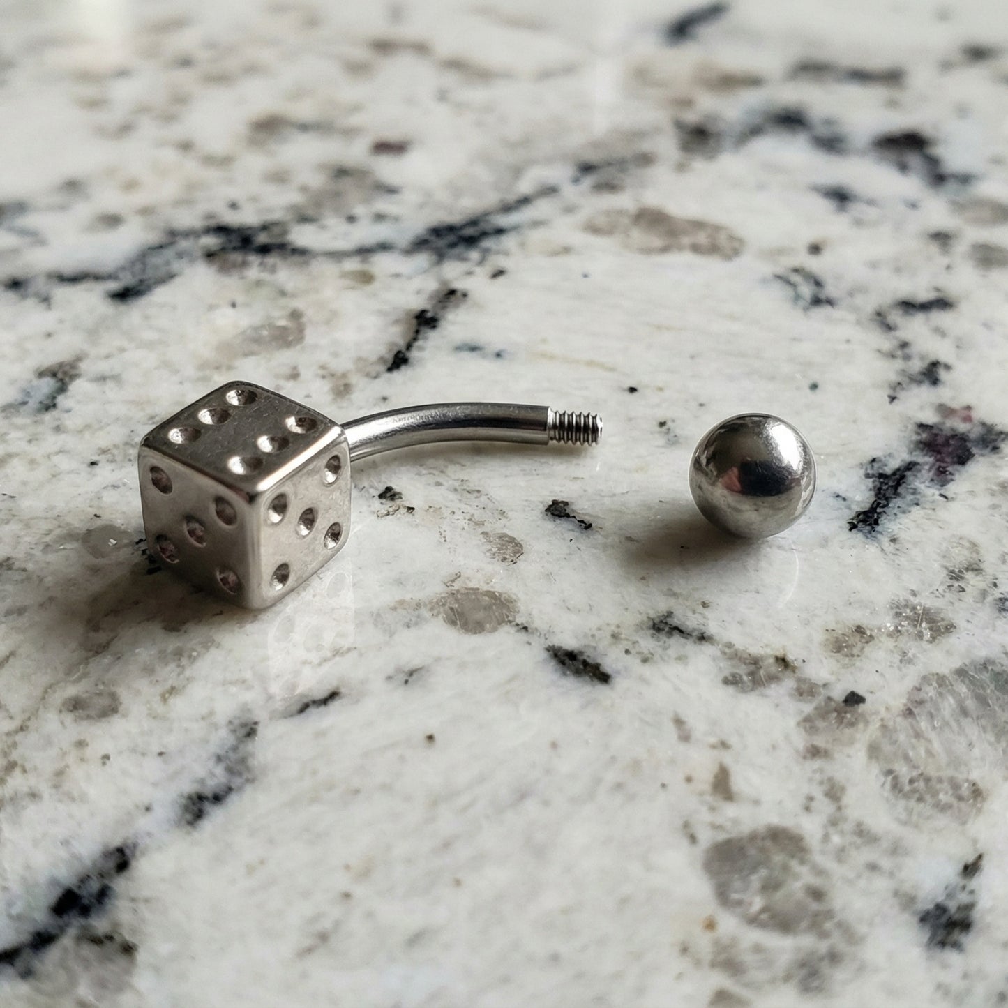 Dice Lucky Gambling Belly Ring 14G 316L Surgical Steel on Countertop.