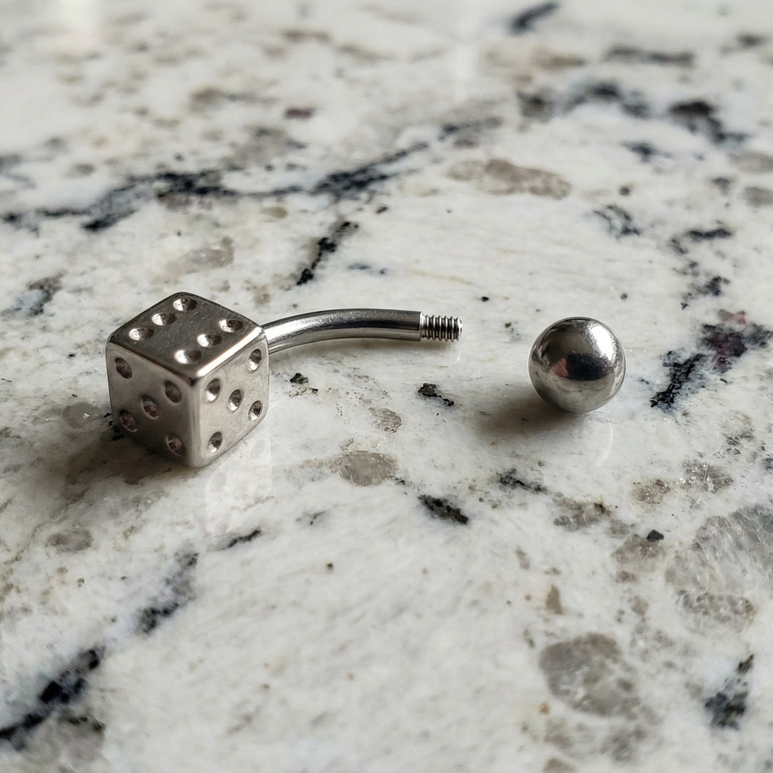 Dice Lucky Gambling Belly Ring 14G 316L Surgical Steel on Countertop.