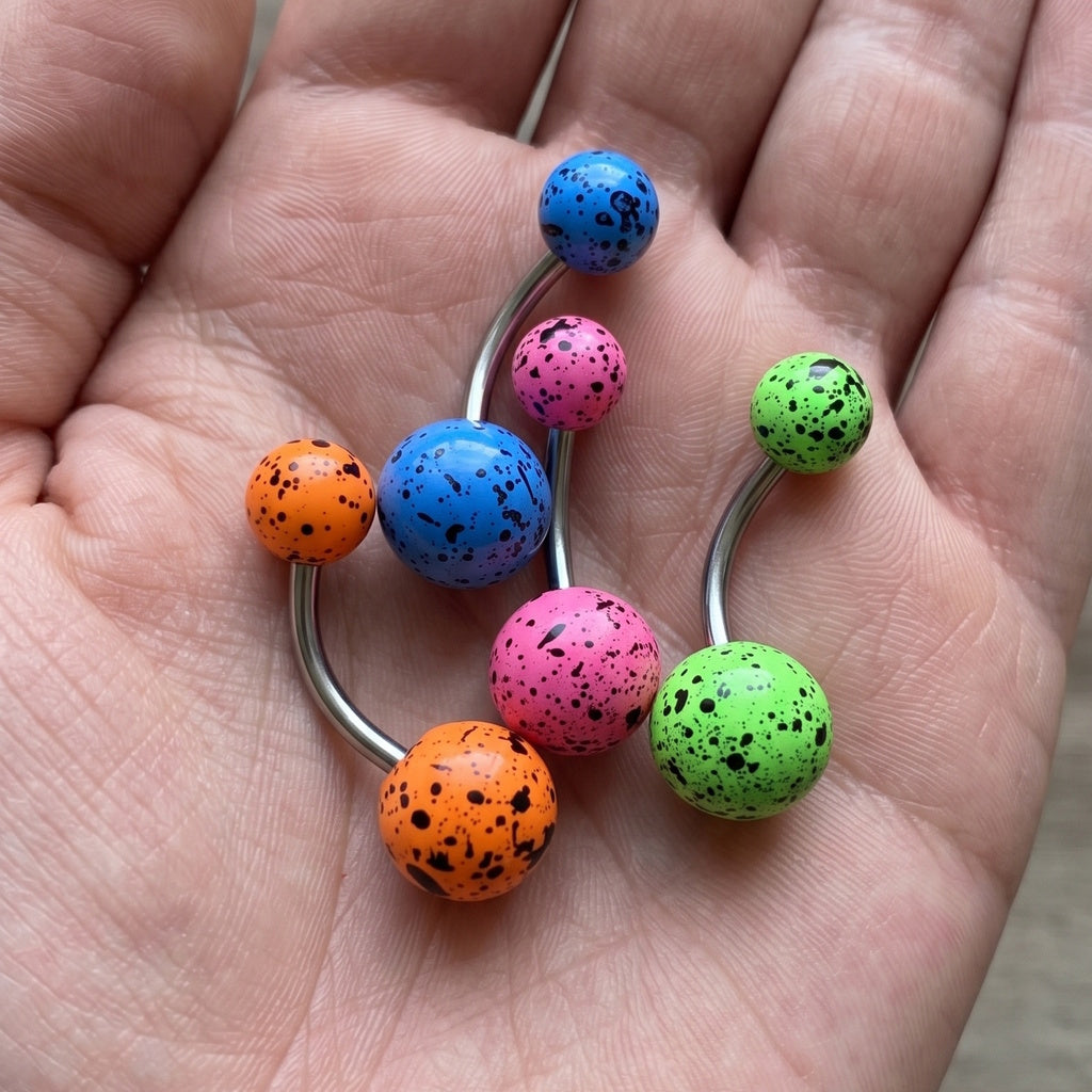 Acrylic Speckled Splatter Belly Ring 14G 316L Surgical Steel in the palm of a hand.